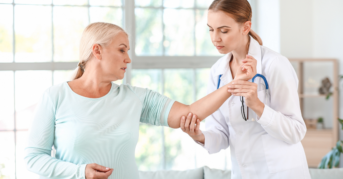 A doctor looks at the elbow joint of her patient.