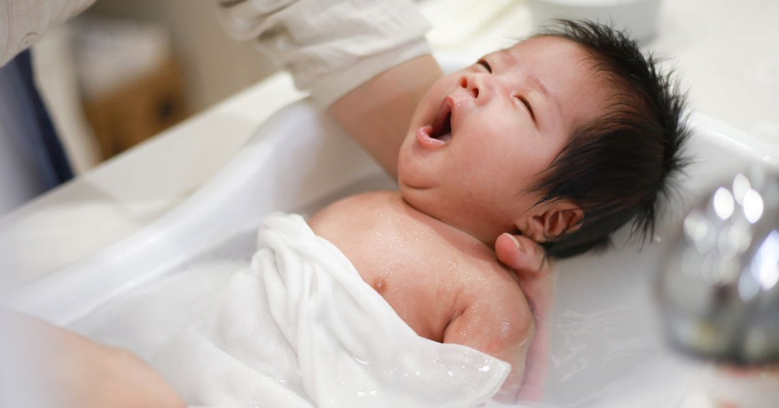 An infant is bathed in a sink. 