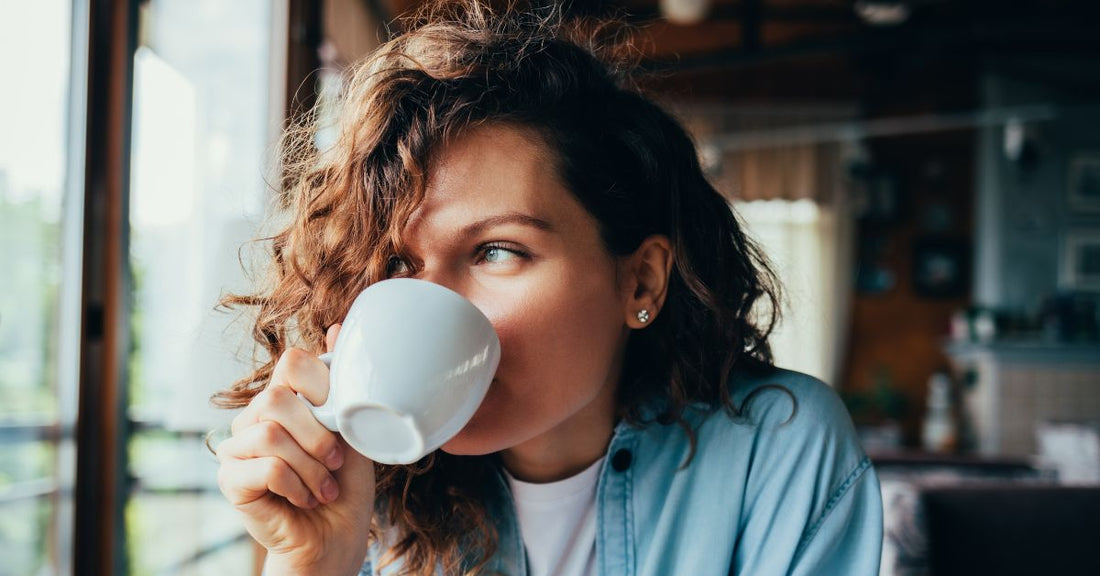 A woman drinks a cup of coffee.