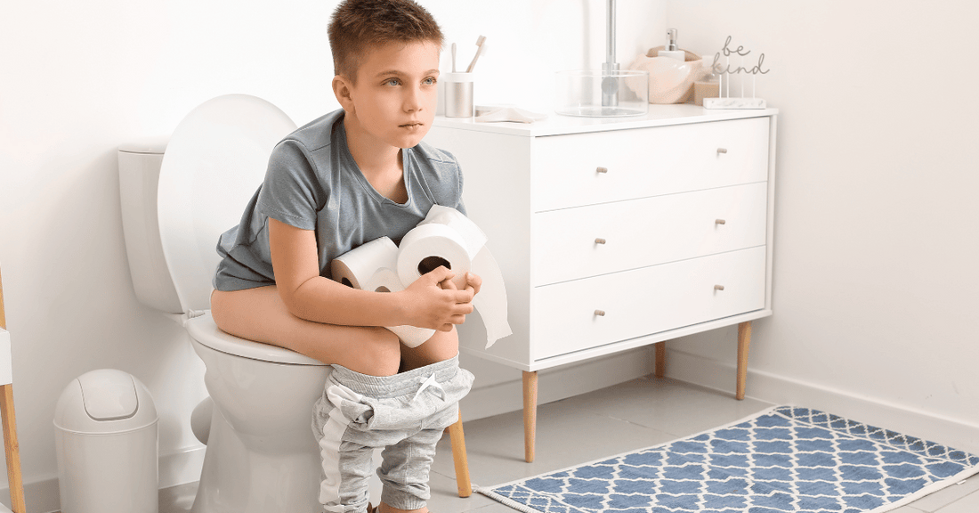 A constipated  boy sits on the toilet.