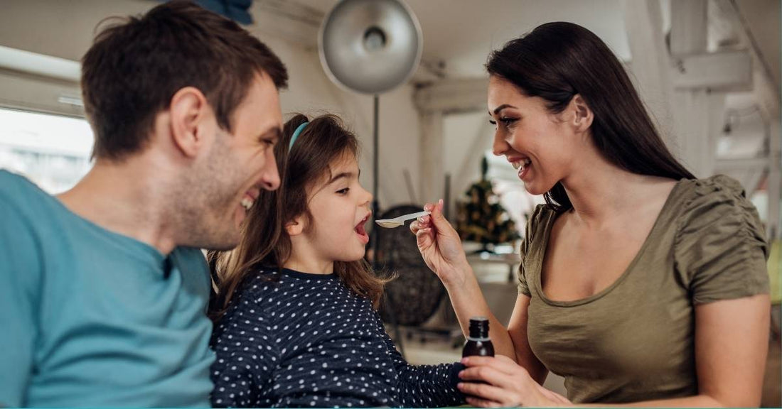 A father and mother give their daughter a spoonful of  medicine.