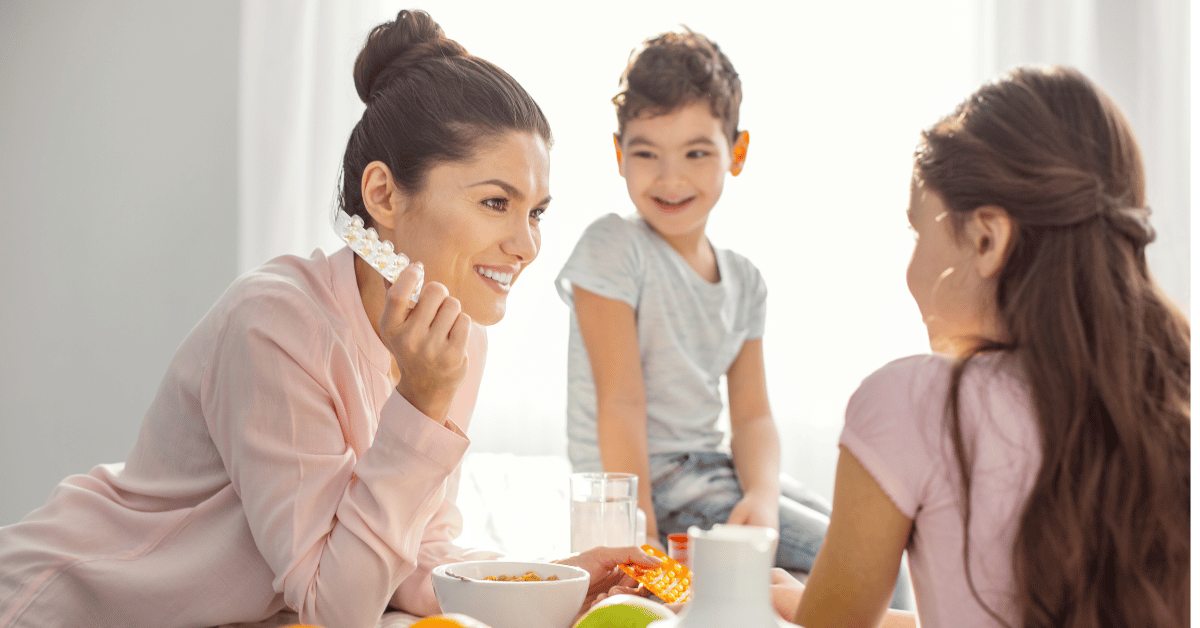 A mother talking to her two children while holding health supplements. 