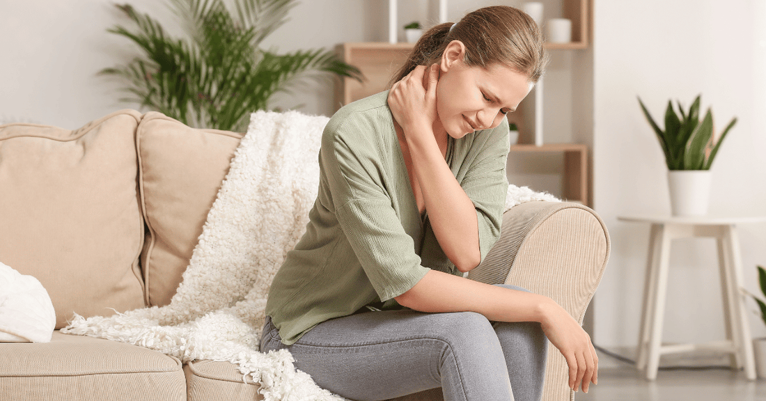 A woman in pain rubs her neck. 