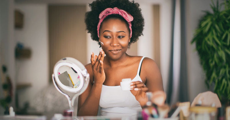 A woman puts moisturizer on her face.