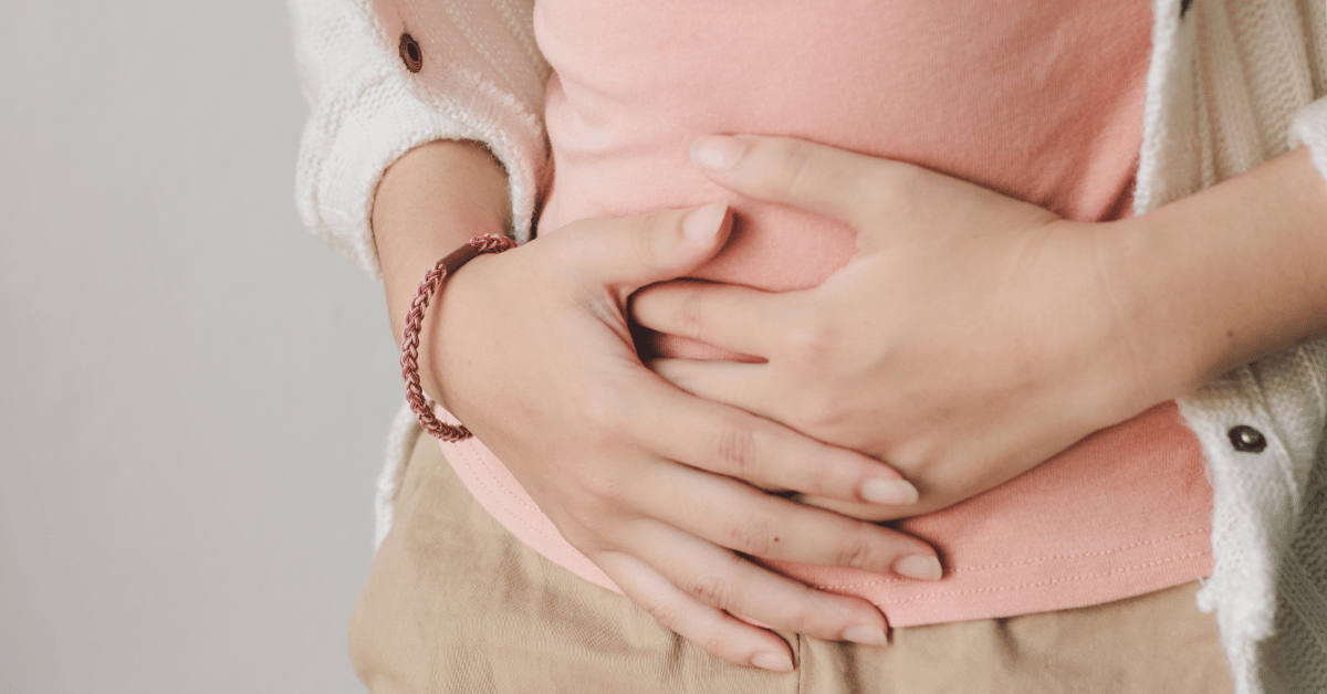 A woman holds her stomach in discomfort.
