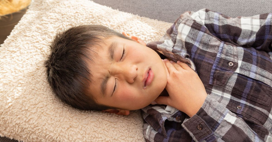 A boy with a sore throat places his hand on his neck.