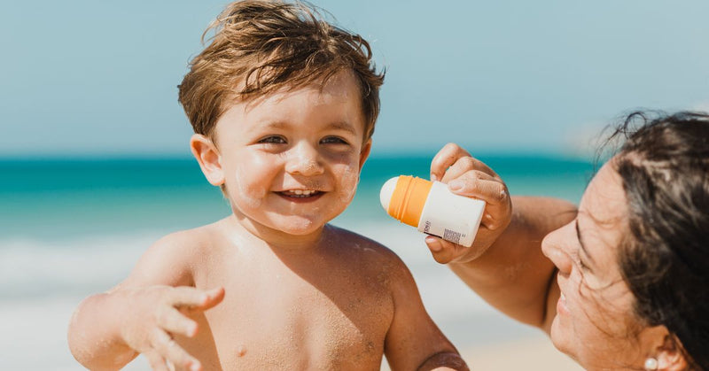 A mom applies sunscreen to her toddler's face.